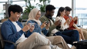 Diverse group of people playing games on unbranded smartphones in a bright public lounge.